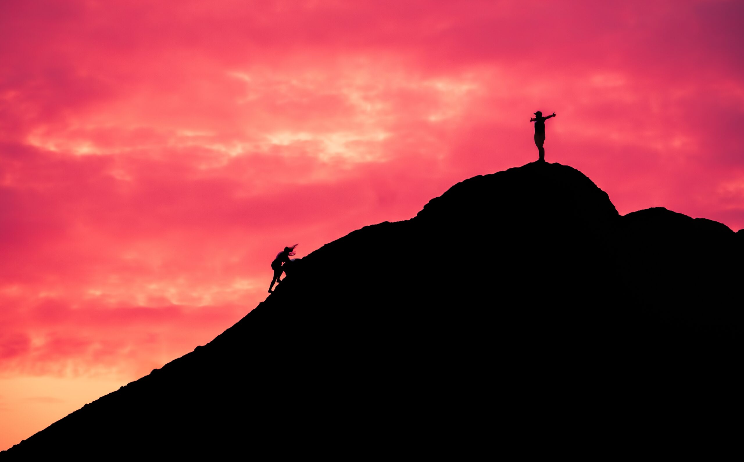 up market two people climbing up a hill at sunset